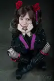 Goth girl in a black jacket with purple trim and fishnet stockings posing at AnimeCon 2010