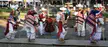 Musicians performing the Danza de los Viejitos in traditional white and red patterned clothing in a public square.