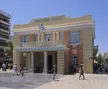 Prefecture of Crete government building with people in casual summer clothing and denim shorts walking in a city square