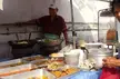 Khun Joe_Jin wearing a red shirt and white baseball cap at an outdoor food stall