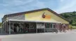Biedronka supermarket with a yellow facade, bicycles, and people in casual streetwear and denim jeans.