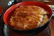 Unadon: glazed grilled eel served over rice in a red bowl