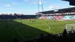 Football stadium in Denmark with players on the soccer field and spectators in the stands under a blue sky