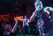 The Exploited, Sensa Yuma, and Zorras Adolescentes performing punk music on stage with a crowd and red lighting