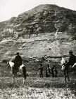 People on horseback and on foot in front of the Mt. of Temptation in a black and white vintage photo
