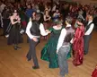 Dancers at The Gaskell Ball in gothic and period-style costumes, including black corsets and red and green gowns.