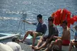 Five friends in casual shorts and baseball caps relaxing on a boat in Cabo, with one man shirtless.