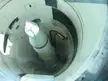 Looking down into a tall white cylindrical silo containing a pointed, multi-segmented torpedo-like object.
