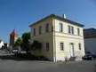 Former school building by August von Voit, a yellow two-story structure on a town street with a red-roofed tower.