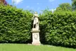 A white classical statue of Ceres on a pedestal in the Belvoir Castle Sculpture Garden, surrounded by green hedges.