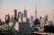 City of Toronto landscape featuring skyscrapers and a tall communication tower under a clear sky.