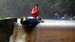 Woman in a red life vest in a blue inflatable boat at the Vyssi Brod Weir waterfall during rain