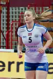 Lucía Fresco, a blonde athletic volleyball player in a white and blue uniform with number 5 on an indoor court.