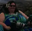Carrie Ann Lucas, a plus-size woman with dark hair and a flower in her hair, wearing a tie-dye floral sundress in a