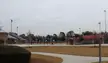 Ted Wright Stadium sports field with bleachers and a brick fence under an overcast sky