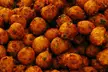 Close-up of golden-brown Bonda, fried savory balls with green herbs.