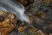 Long-exposure landscape photography of flowing water over brown rocks in a Colorado stream.