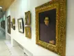 Fine art oil paintings in frames hanging on a white gallery wall for an art exhibition.