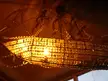 Ship-shaped chandelier with crystals and a metal frame hanging in a vintage tavern