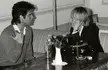John Travolta and Kersti Adams-Ray talking on a sofa in a black and white vintage photo