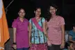 Three Indian women with dark hair and brown skin standing outdoors at night, one with henna on her hand.
