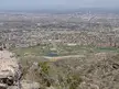 High-angle view of a city skyline and golf course from a rocky hillside at South Mountain