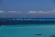 Beach of La Pelosa with sailboats anchored in a turquoise ocean and a group of people swimming