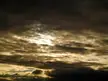 Aesthetic 4k desktop wallpaper of a dark, cloudy sky with sunlight breaking through the center.