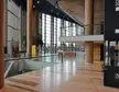 Müpa Budapest interior with wooden columns, glass railings, large windows, and a silhouette standing on a polished floor
