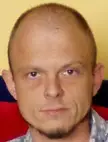 Wilco Melissant with a shaved head and goatee wearing a light-colored patterned shirt against a yellow wall