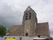 The church in Cheptainville, a stone church with a clock tower, white tents, and a yellow umbrella in Essonne
