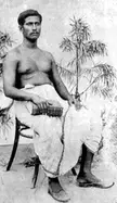 Rajanikanta Sen, an athletic man with dark skin, sitting shirtless with a white waist wrap and a book