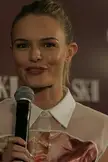 Kate Bosworth smiling with blonde hair tied back, wearing a white collared shirt and holding a microphone