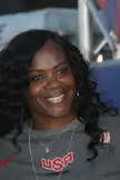 Swoopes smiling in a grey USA Basketball t-shirt with long curly black hair.