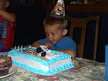 Evan wearing a party hat at a table with a Spiderman toy car cake
