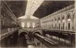 Stazione: a vintage black and white gravure of a train station interior with a mezzanine and glass roof