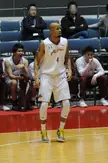 Raymond Nixon in a white basketball uniform with tattoos on his arms, standing on a court with teammates.