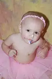 JB 021 wearing a pink headband and tutu with cake frosting on their face