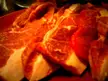 Cursed food image of raw, sliced red meat with white fat marbling on a red plate.