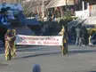 Two people in biblical costumes holding a banner that reads 'Christmas is Christ, God's Gift to Mankind' in a parade.