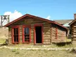 The Park County courthouse log cabin with red frames and a mining headframe in a Colorado landscape.