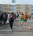 Runners in athletic wear, tights, and sneakers participating in a road race on a city street.