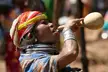 A Bonda tribeswoman with dark skin wearing a colorful headwrap and silver neck rings drinking from a gourd
