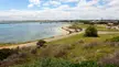 Port Denison and its Boat Harbour coastal scene with a sandy beach, clear blue water, and a small parking area