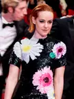 Jena Malone in a black sequined floral dress with a man in a tuxedo on a red carpet