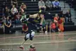 Roller derby skater in a black tank top, tights, and helmet with a gold star skating past spectators in an arena