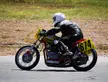 Chris Hovland in a black leather racing suit and white helmet riding a red and yellow motorcycle on a track
