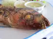 Cursed food: a grilled red snapper on a white plate with rice, sauce, and a lemon slice.