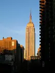 Empire State Building and skyscrapers in a city skyline under a clear blue sky during golden hour